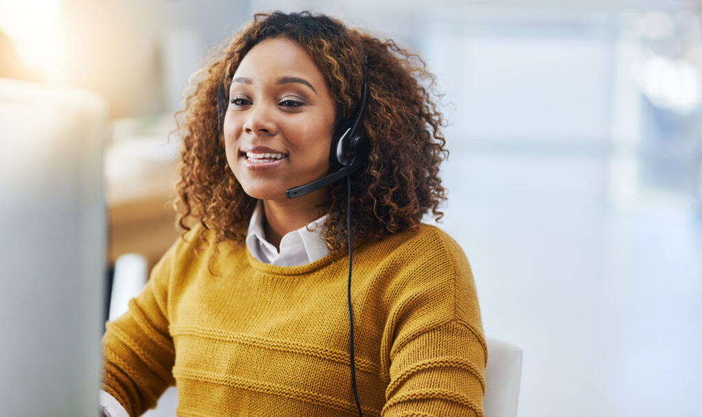 A women with a headset smiling at her computer