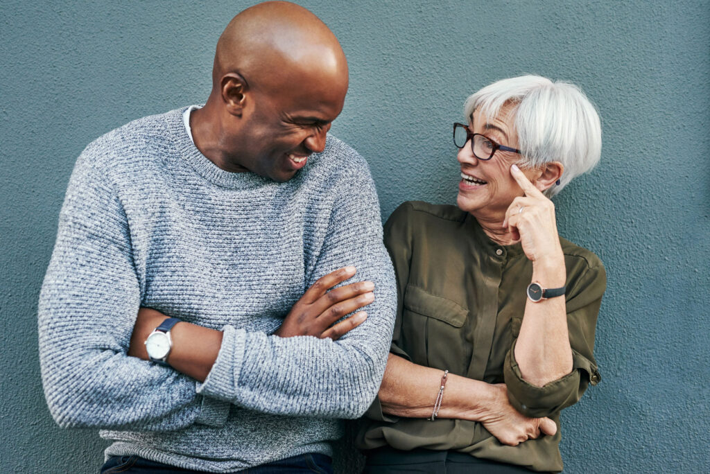 Shot of two cheerful mature businesspeople having a discussion while standing against a wall outdoors.