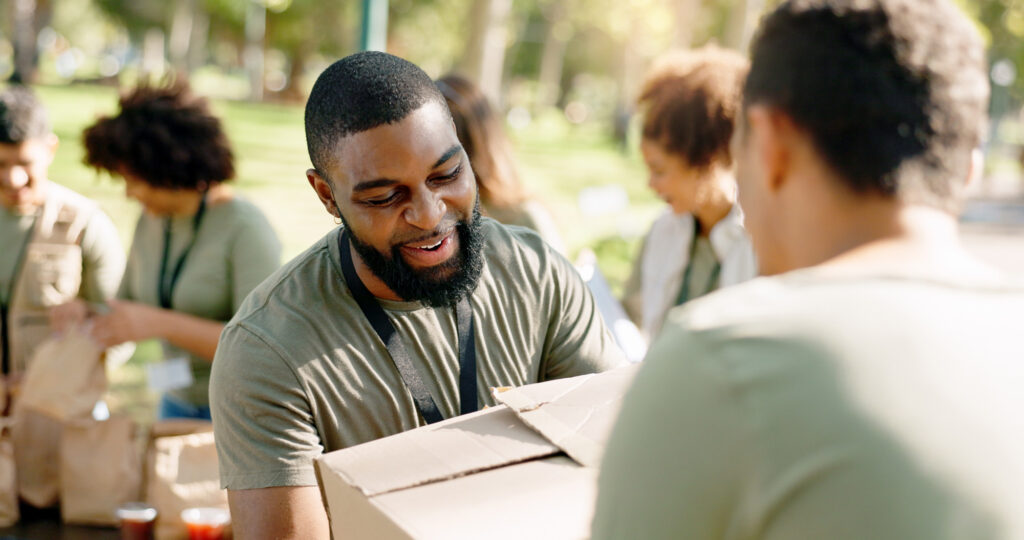 Charity, cardboard boxes and volunteer in park for donation, distribution or community service. Help, NGO and people with package for support, kindness or social responsibility with teamwork.